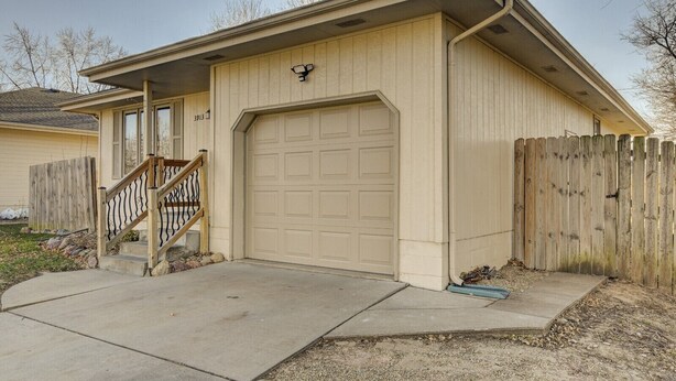 A single-story house with a garage, a wooden staircase, and a wooden fence.