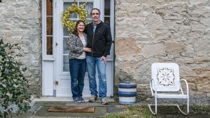A stone building with a white door, a metal chair, and a decorative wreath. - Luxury in a Historic Landmark-great restaurants within walking distance! (Clarence)