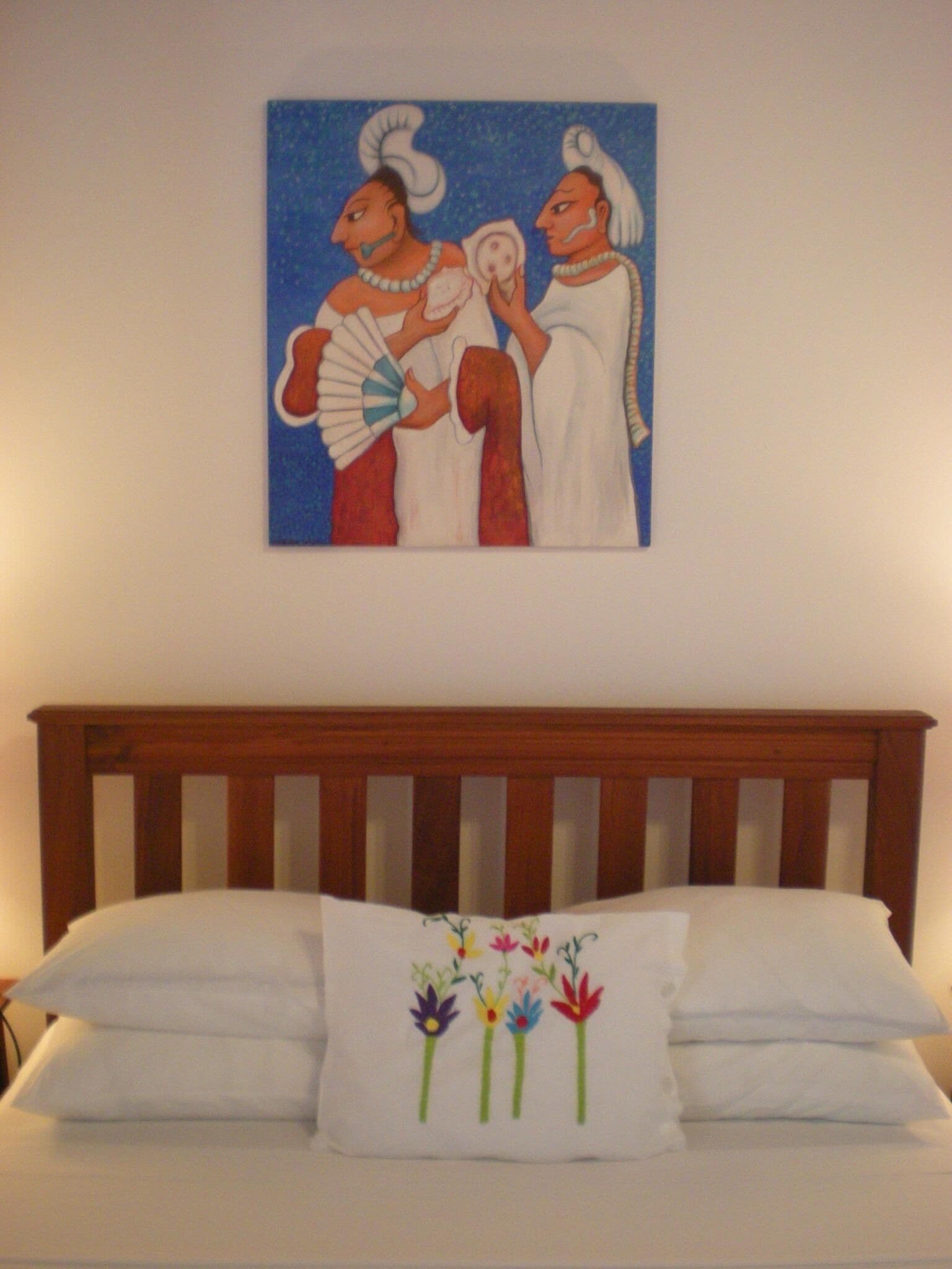 Una cama con cabecera de madera y almohada con diseño floral.