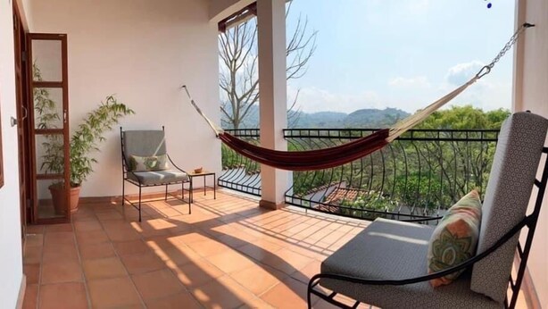 Un balcon avec un hamac, une chaise et une table.