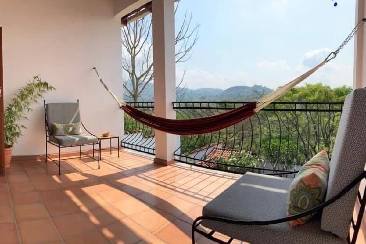 A balcony with a hammock, a chair, and a table.