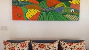 Un tableau représentant des champs aux couleurs vives et une petite maison située sur une colline.