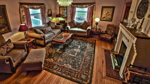 A traditional living room with a fireplace, wooden flooring, and classic furniture.