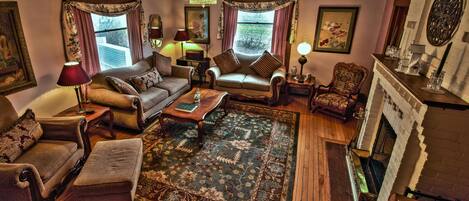 A traditional living room with a fireplace, wooden flooring, and classic furniture.