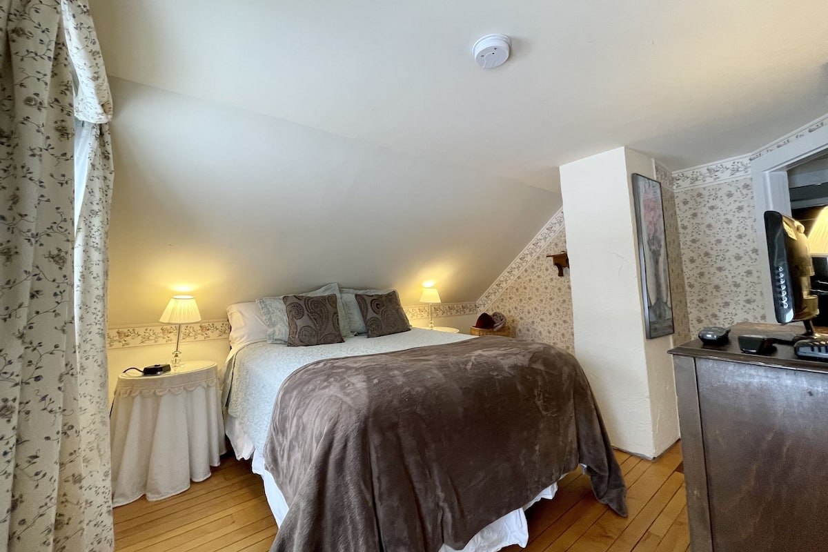 A bedroom with a bed, bedside lamps, a dresser, and a ceiling light.