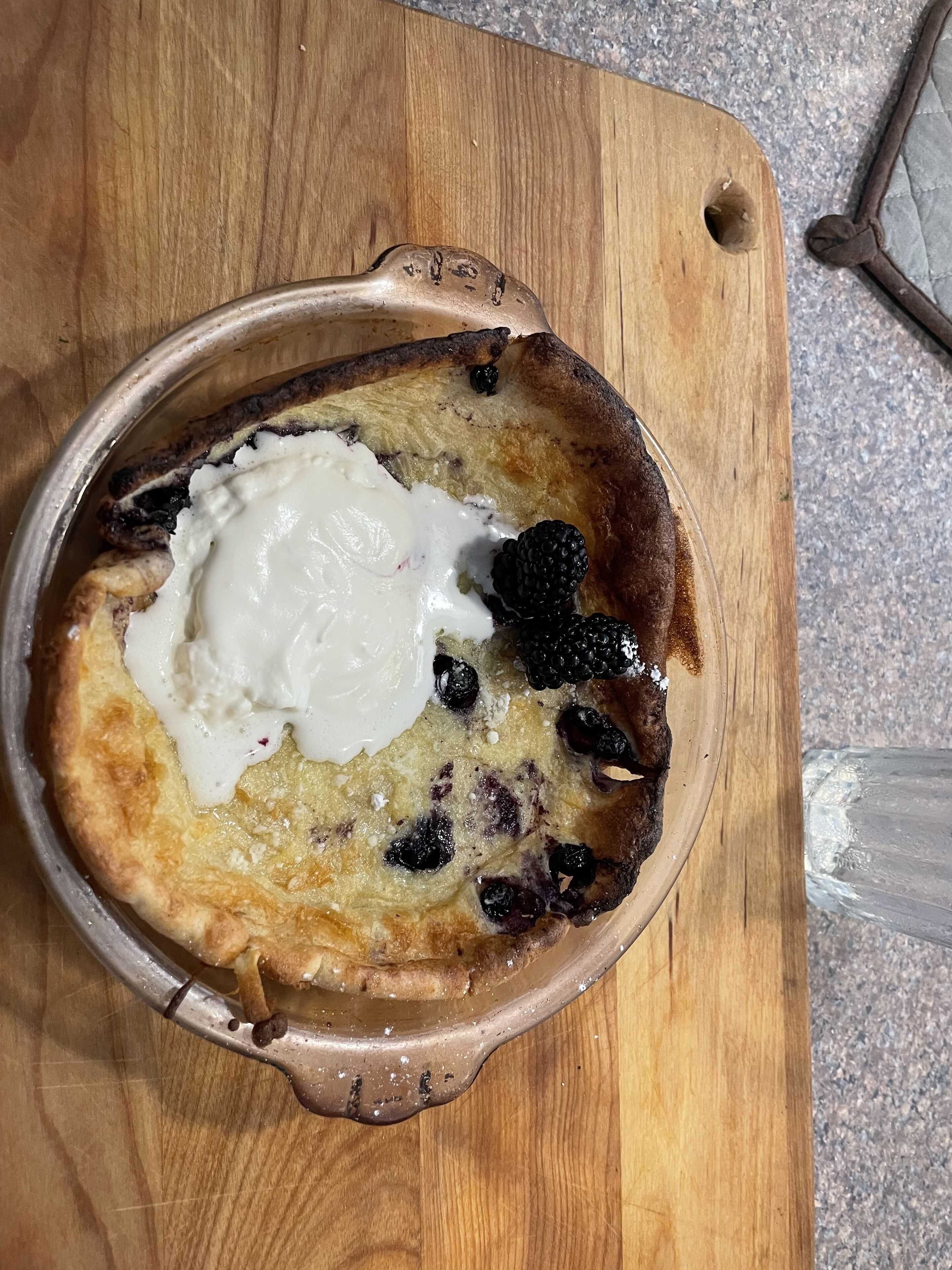 Un dessert servi dans un plat en céramique, posé sur une planche en bois.