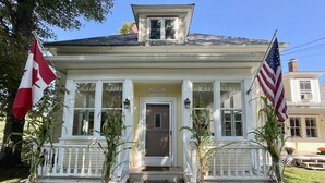 A two-story house with a porch, a guest entrance sign, and two flags.