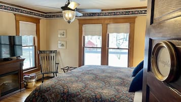 Un dormitorio con colcha estampada, cómoda de madera, televisor y una silla.