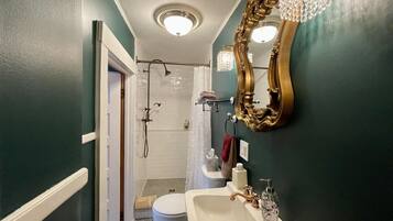 A bathroom with a white sink, a gold mirror, and a shower.