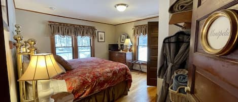 A bedroom with a bed, bedside table with lamps, a dresser, and a coat rack.