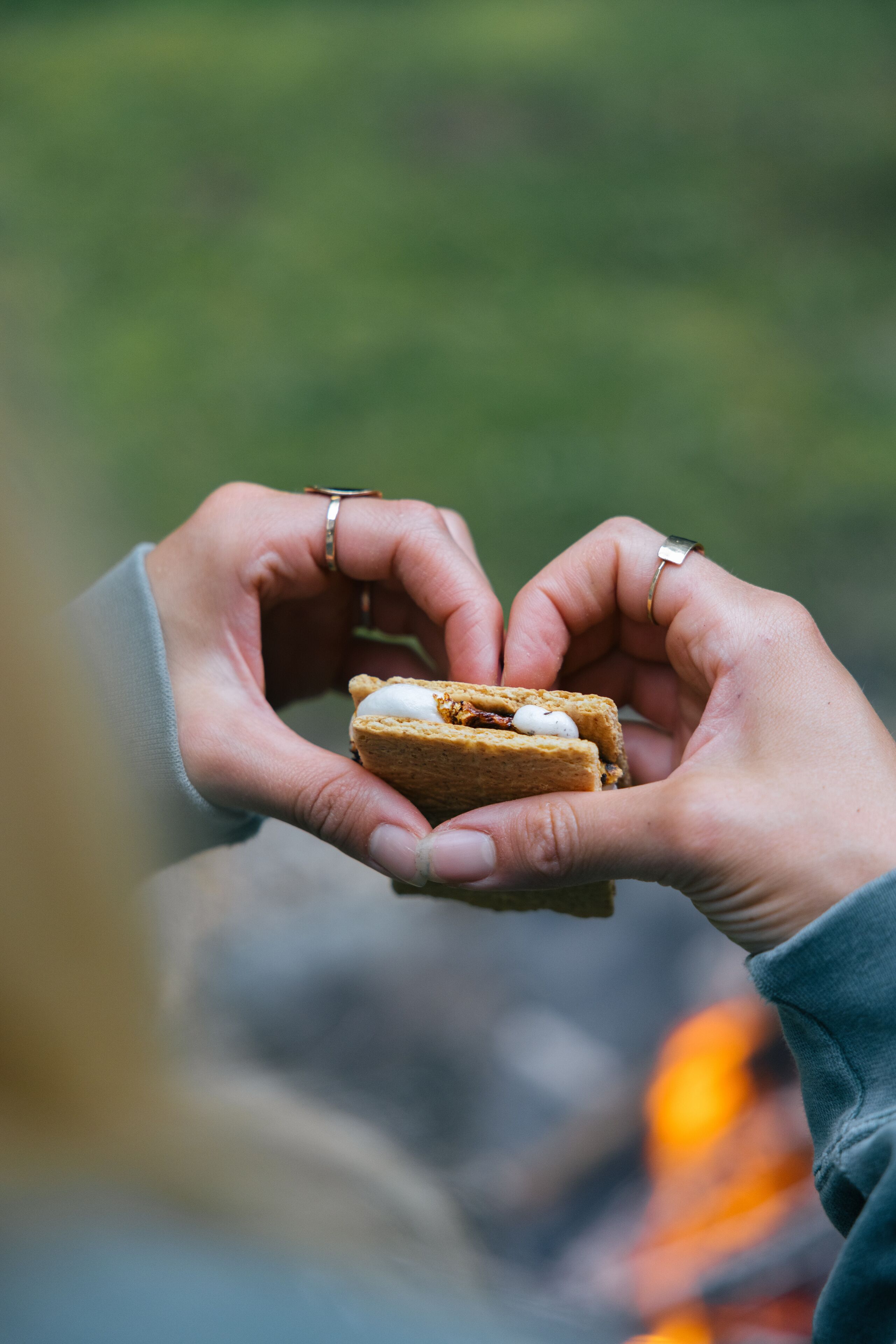A person holding a sandwich with a heart shape made by their hands.