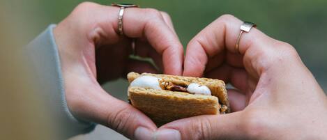 A person holding a sandwich with a heart shape made by their hands.