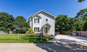 Classic two-story residence with a central entrance, surrounded by a well-maintained lawn and mature trees.