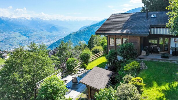 Eine Chalet mit Terrasse, Essbereich und Bergblick.