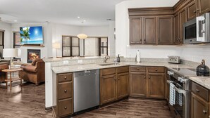 Une cuisine moderne avec des meubles en bois, des appareils en acier inoxydable et un plan de travail en granit.