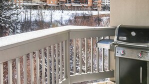 Un balcon doté d’un barbecue Weber Spirit, offrant une vue sur un paysage enneigé et des immeubles à plusieurs étages.