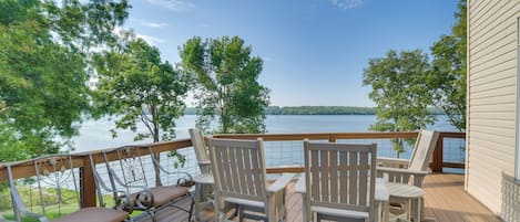 A deck with Adirondack chairs overlooking a lake.