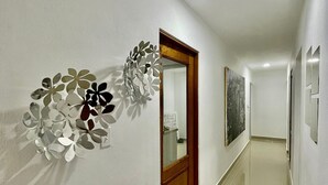 Ein Korridor mit einer Holztür, einem Wanddekor und einem gefliesten Boden.