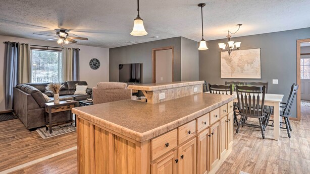 A modern kitchen with a central island, wooden cabinets, and a dining area with chairs and a table.