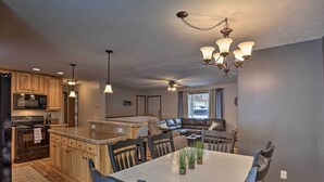 A modern kitchen with wooden cabinets, a built-in microwave, and a large island with bar stools.