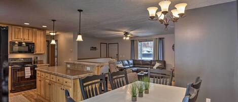 A modern kitchen with wooden cabinets, a built-in microwave, and a large island with bar stools.