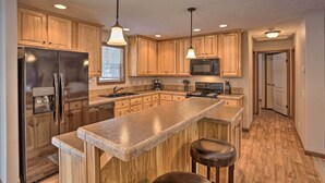 A modern kitchen with wooden cabinets, stainless steel appliances, and a central island with bar stools.
