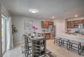 A modern kitchen with wooden cabinets, a stainless steel refrigerator, and a built-in island with bar stools.