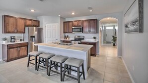 A modern kitchen with wooden cabinets, stainless steel appliances, and a central island with bar stools.