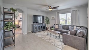 A modern living room with a grey sofa, a coffee table, a TV, and a ceiling fan.