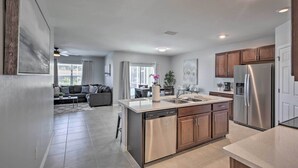 A modern kitchen with a dishwasher, stainless steel refrigerator, and wooden cabinets.