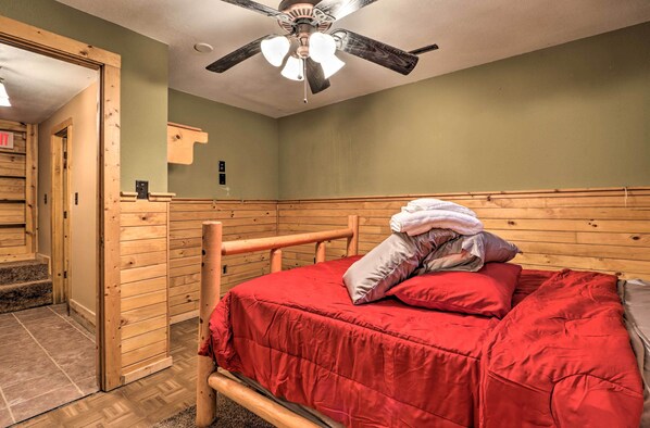 Una habitación con una cama de madera, un ventilador de techo y una escalera que lleva a un nivel superior.