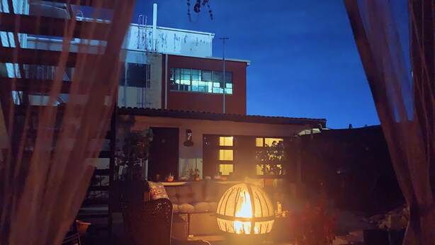Un área de patio con una chimenea, una silla y un edificio al fondo.