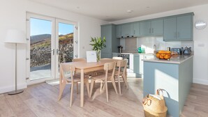 Una cocina moderna con armarios azul claro, una mesa de comedor de madera y vistas por la puerta de cristal.
