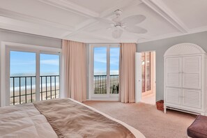 Relax in this serene room with a large bed and stunning beach views, featuring a ceiling fan, wardrobe, and balcony.