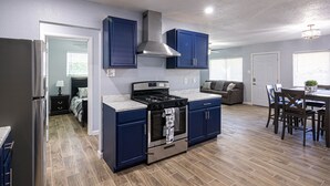A modern kitchen with dark blue cabinets, a stainless steel stove, and a large oven. - Charming 3 Bedroom residential home with parking on site. (El Paso)