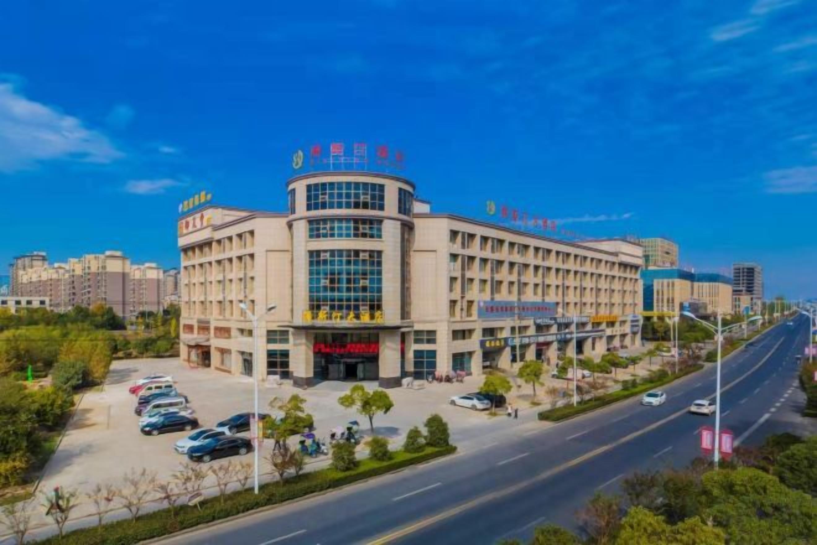 A multi-story building with a curved facade, multiple entrances, and a parking lot in front.