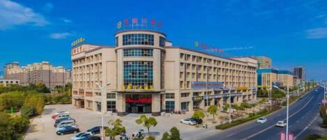 A multi-story building with a curved facade, multiple entrances, and a parking lot in front.