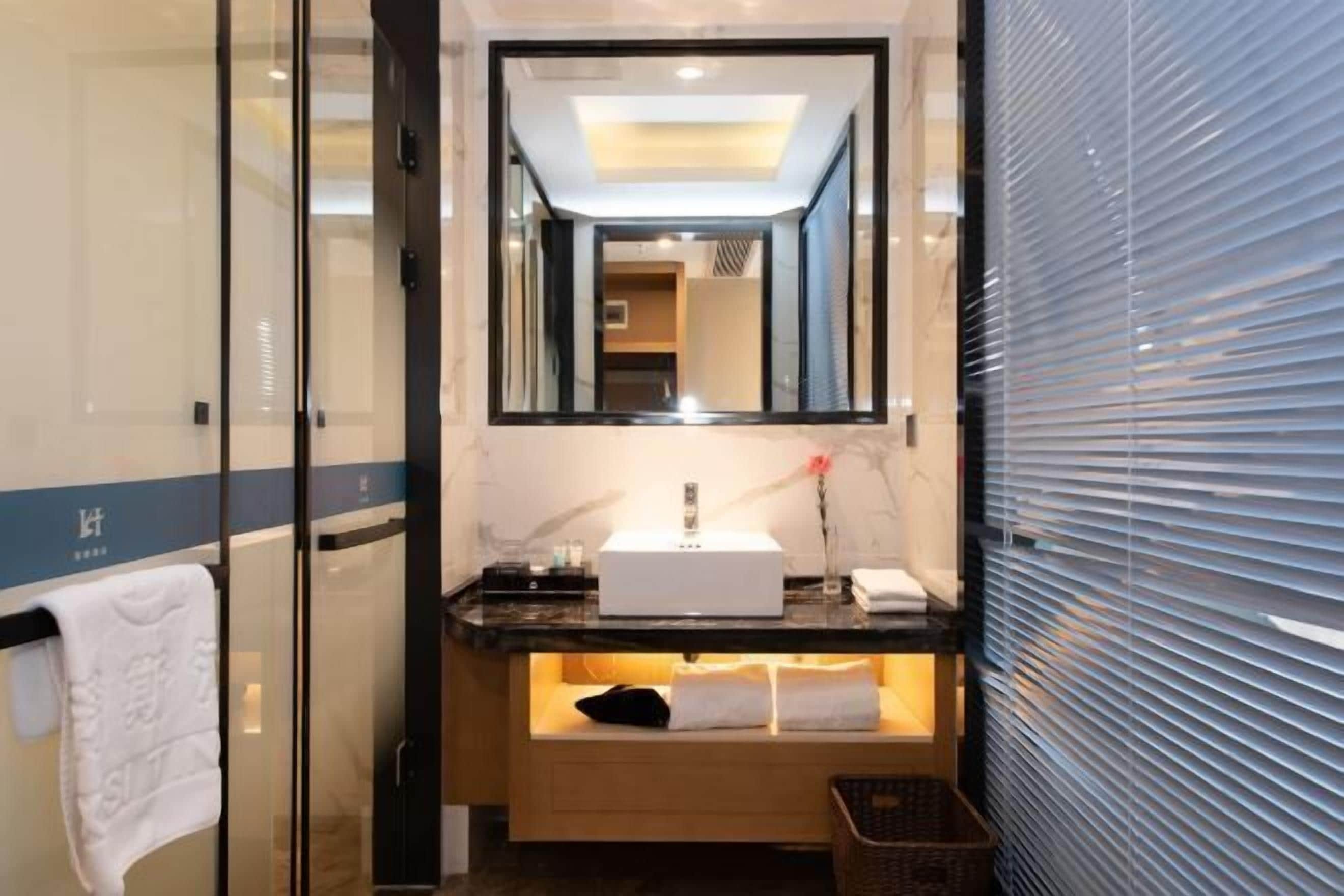 A modern bathroom with a glass shower enclosure, a white sink, and a mirror above it.