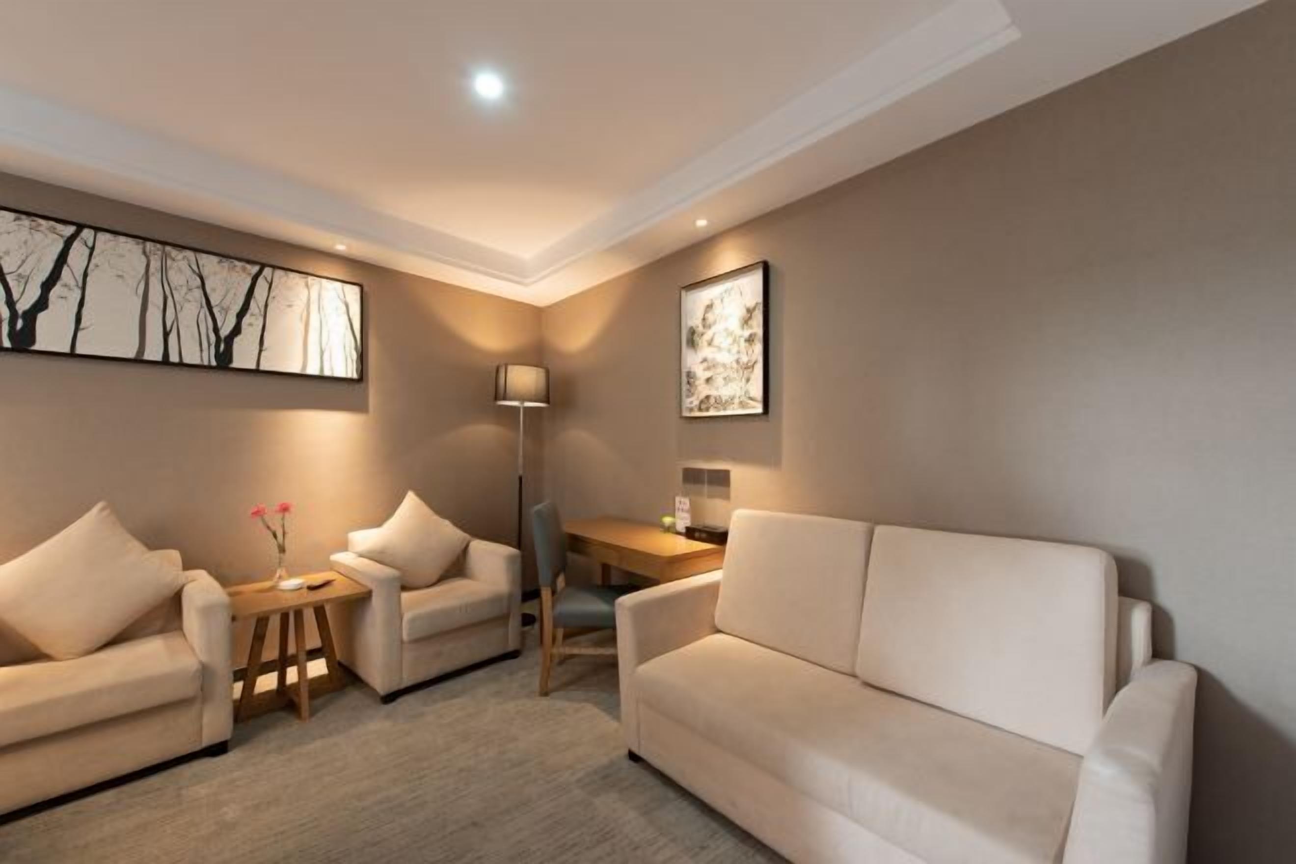 Un salon moderne comprenant un canapé, des fauteuils, une table basse, un bureau et deux œuvres d’art accrochées au mur.