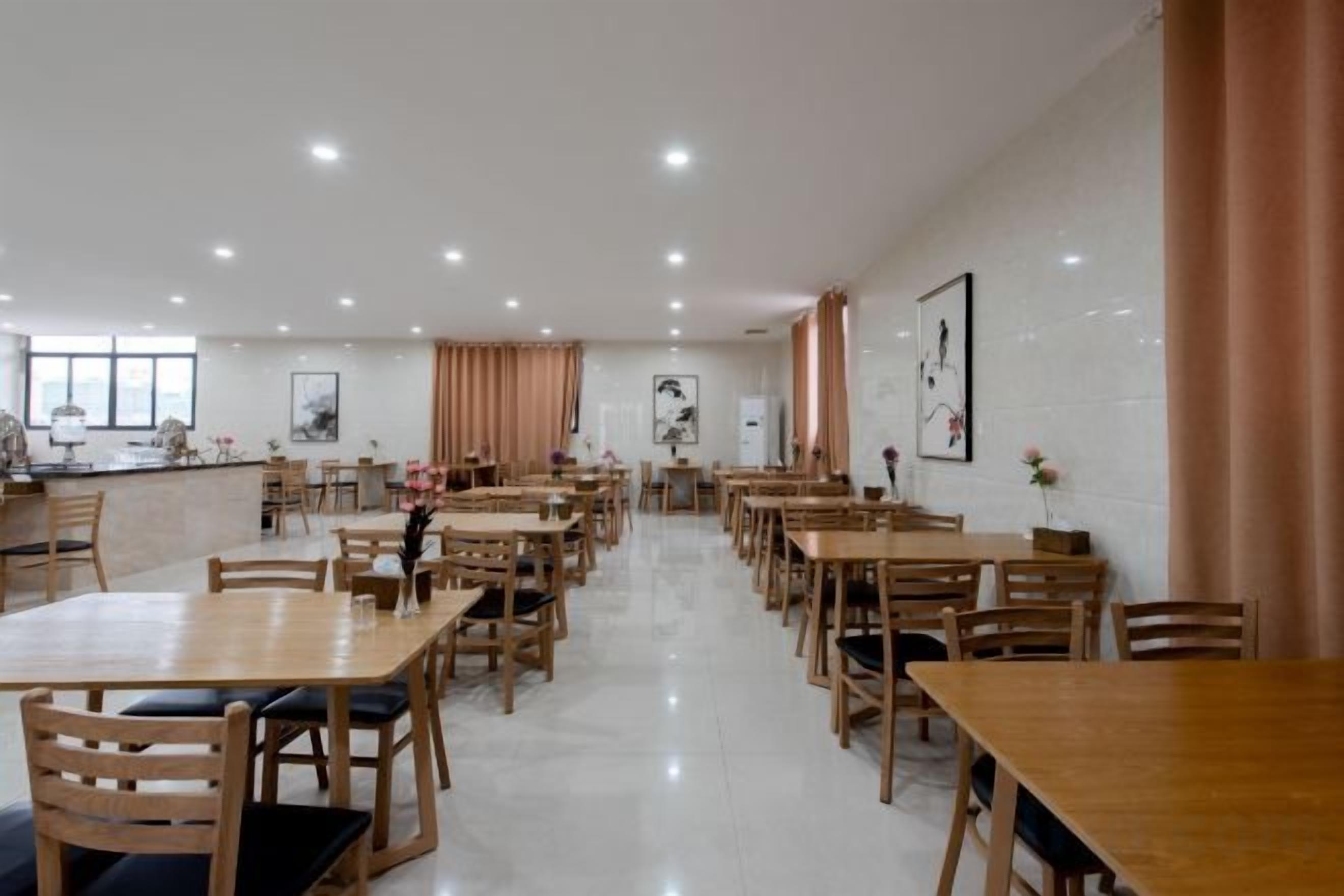 A spacious dining area with multiple wooden tables and chairs, a bar counter, and artwork on the walls.