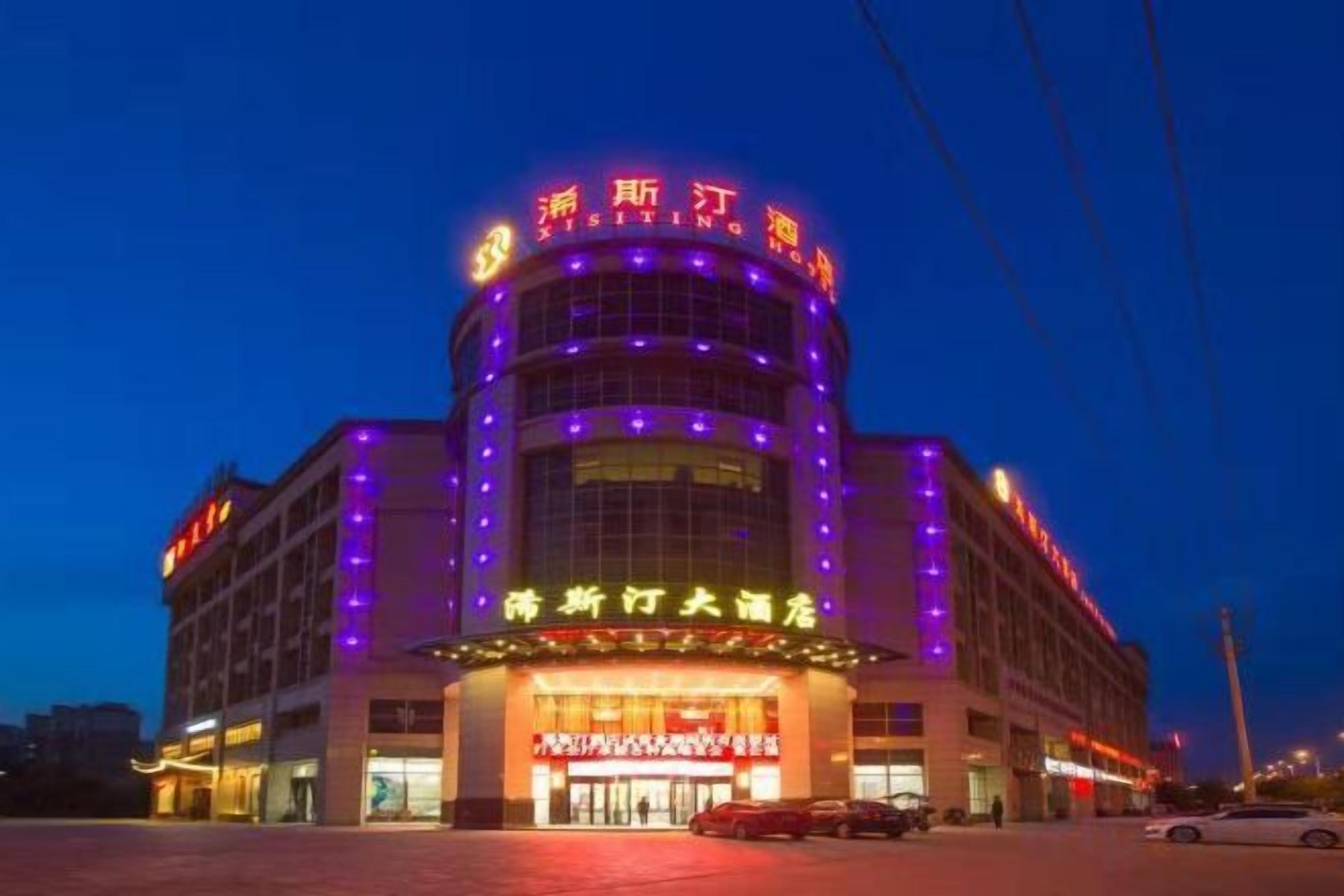 A hotel with a prominent entrance, multiple floors, and illuminated signage.