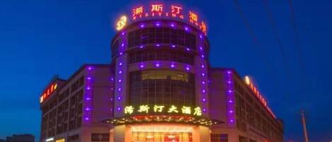 A hotel with a prominent entrance, multiple floors, and illuminated signage.