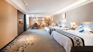 Une chambre d’hôtel avec deux lits, un coin salon avec une table et des chaises, et une grande fenêtre.