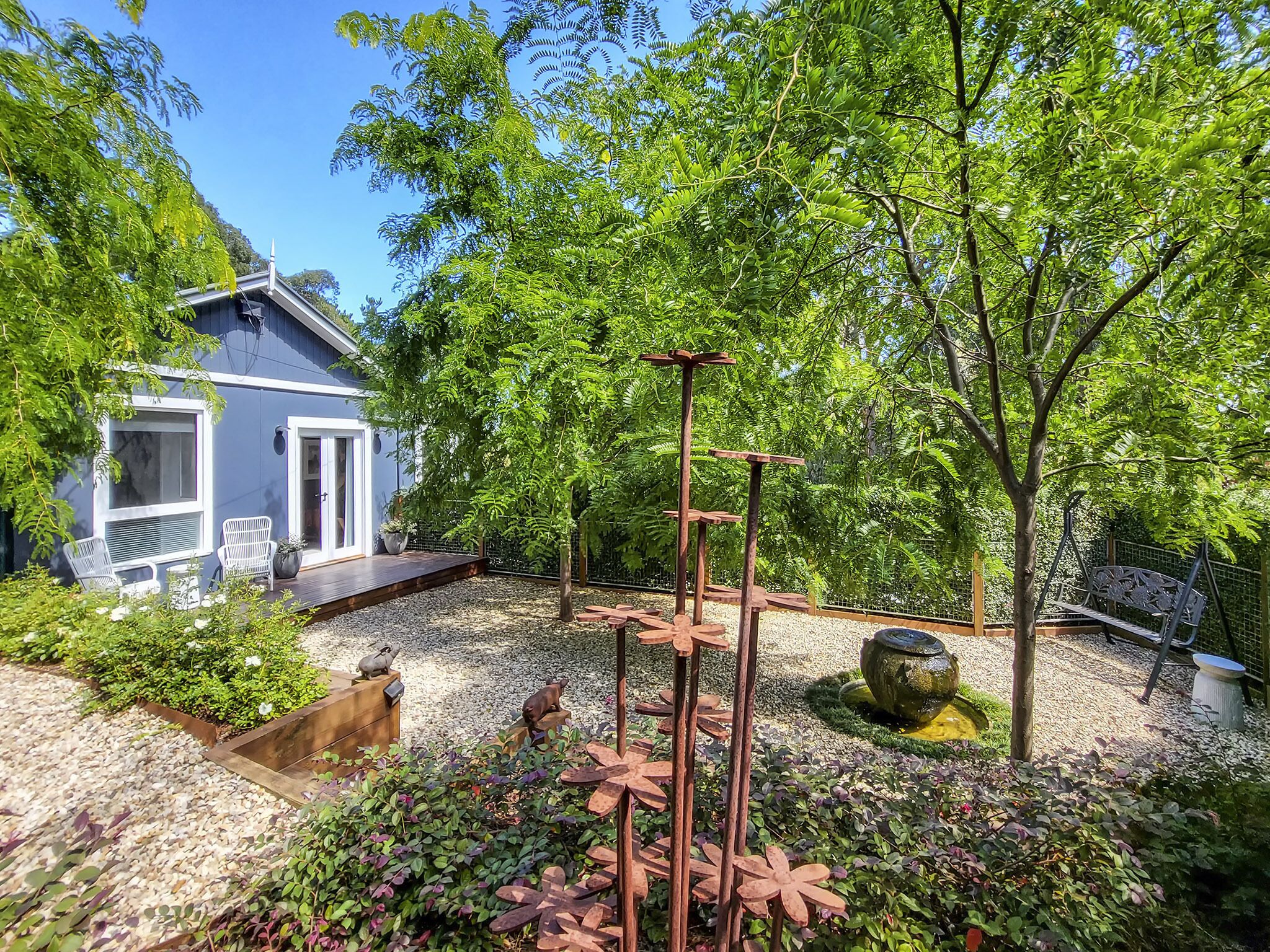 A garden with a patio, seating area, and a small house.