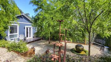 A garden with a patio, seating area, and a small house.