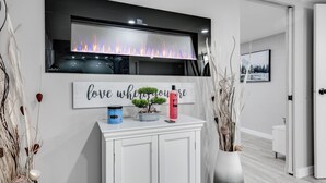 Un baño moderno con chimenea, tocador con espejo y plantas decorativas.