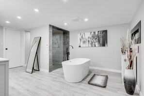 Une salle de bain moderne avec une baignoire sur pieds, une douche à l’italienne et un design minimaliste.
