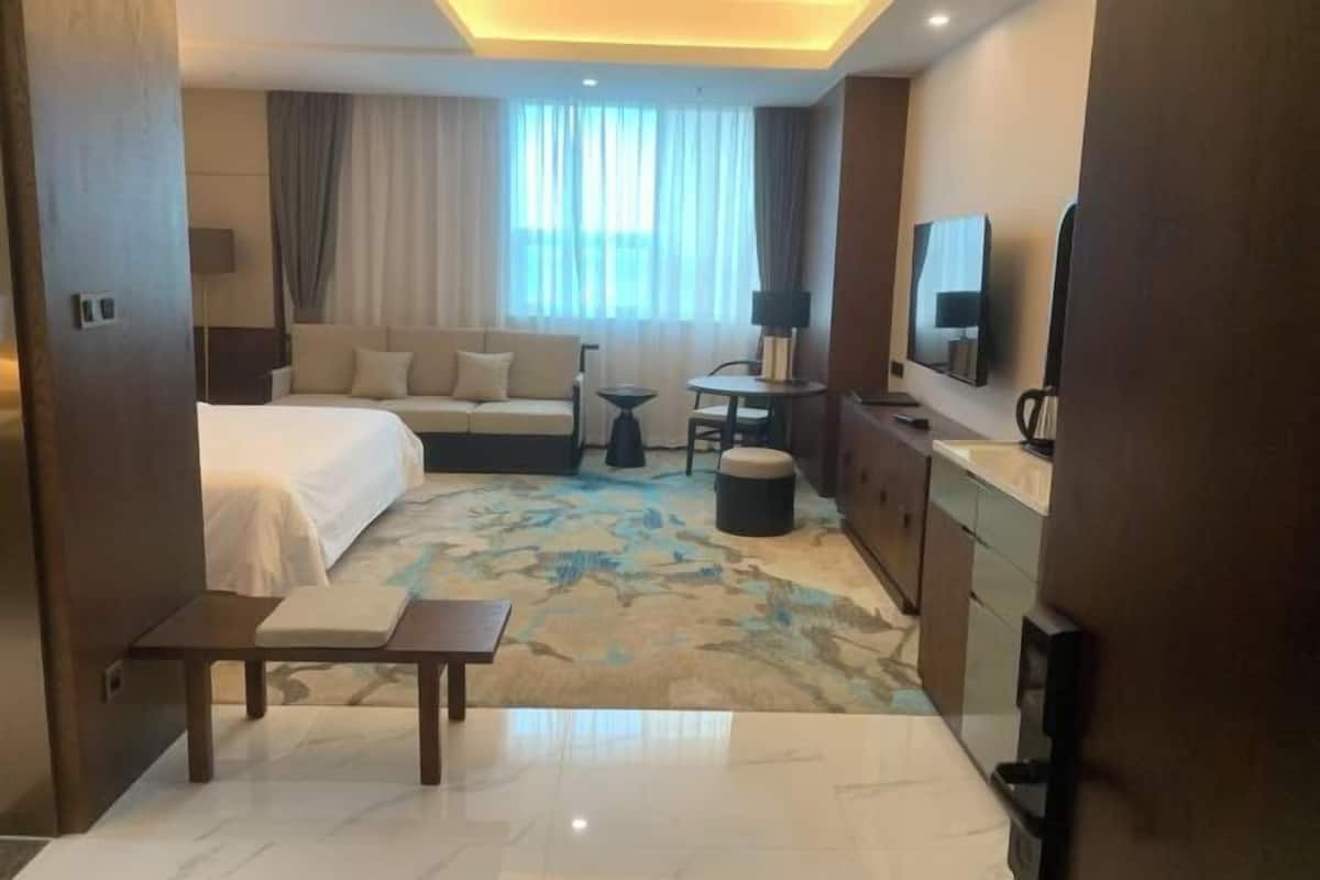 Une chambre d’hôtel comprenant un lit, un canapé, une petite table, une télévision et un coin cuisine.
