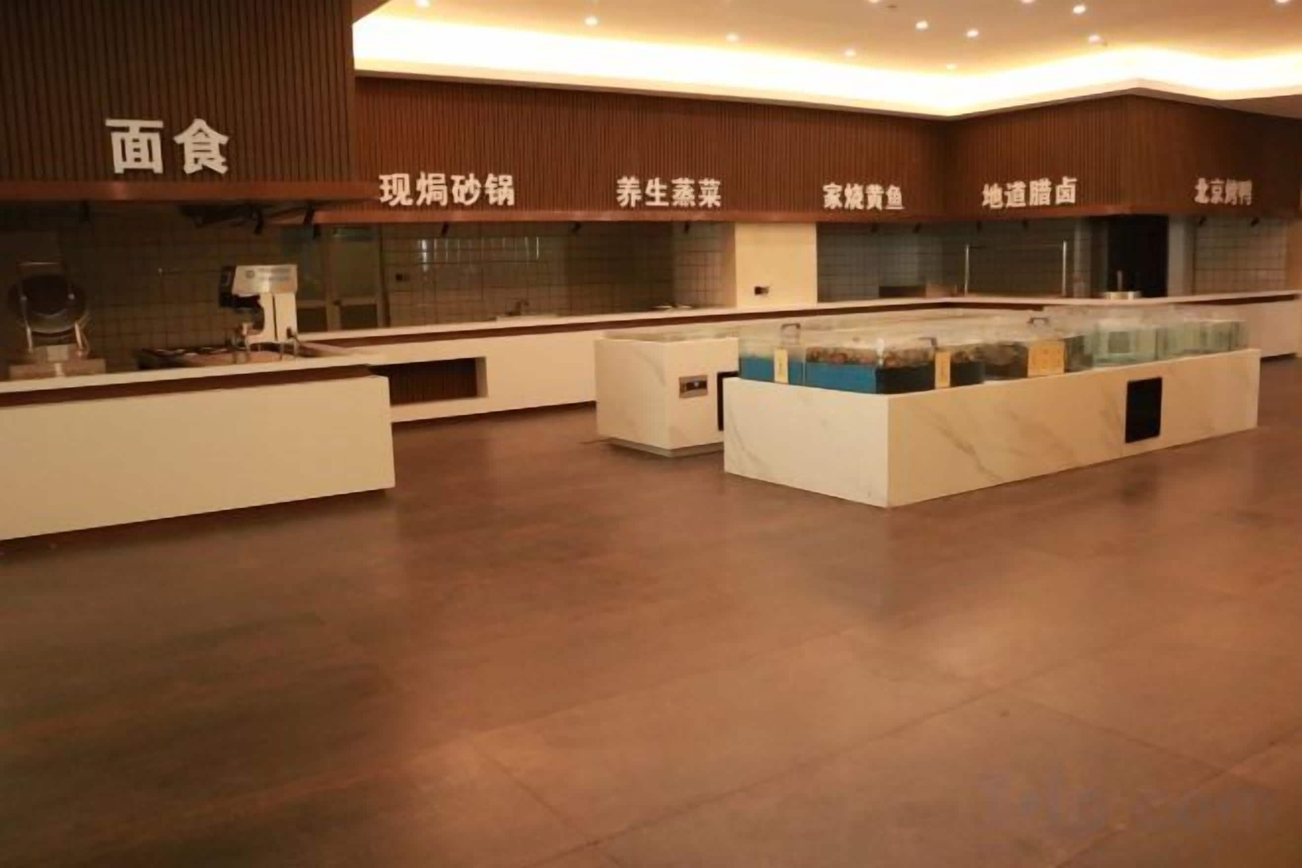 A modern hotel lobby with a reception desk, a seating area, and a counter with food options.