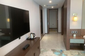 Una camera d'albergo moderna con TV a schermo piatto, macchina del caffè, comodino e tavolino di fianco al letto.